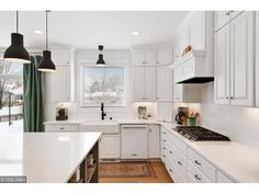 a kitchen with white cabinets and counter tops