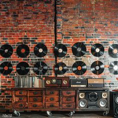 an old record player sitting in front of a brick wall with records hanging on it