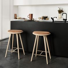 two wooden stools sitting in front of a black counter