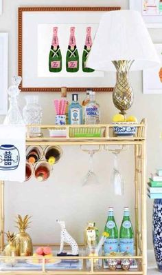 a bar cart with bottles and glasses on it in front of a framed photo above the bar