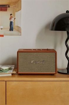 an old fashioned radio sitting on top of a wooden dresser next to a lamp and pictures