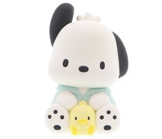 a white and black dog figurine sitting on top of a yellow duck