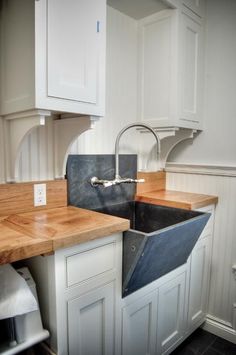 a kitchen with white cabinets and wooden counter tops