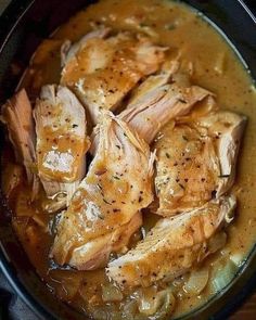 some chicken is cooking in a pot with gravy on the side and garnished with parsley