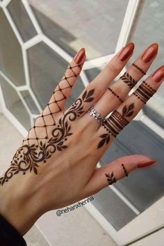 a woman's hand with hennap tattoos on her fingers and wrist,