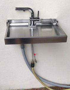 a stainless steel sink and faucet attached to the wall with a hose connected to it