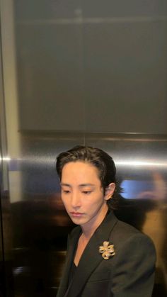 a man in a suit is looking at his cell phone while standing next to an elevator