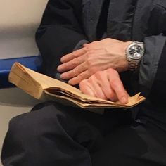 a person sitting on a bench with their hands folded over an open book in front of them