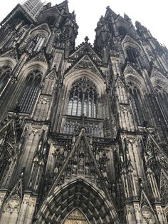 an old cathedral with many windows and statues on the front wall, looking up into the sky