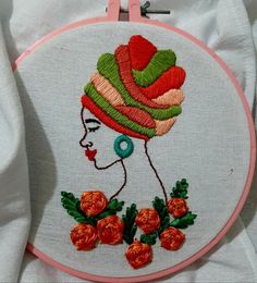 a close up of a embroidery on a piece of cloth with an image of a woman wearing a hat