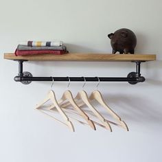 three wooden clothes hangers on a shelf with a pig figurine next to them