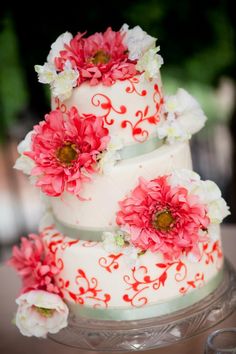 a three tiered wedding cake with red and white flowers