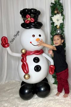 a little boy standing next to a giant snowman