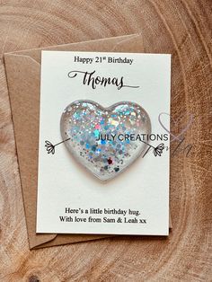 a birthday card with a heart shaped brooch sitting on top of a piece of wood