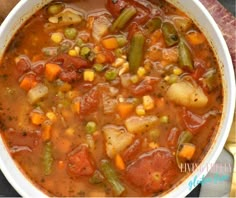 a white bowl filled with vegetable soup on top of a table