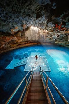 the stairs lead up to an underground pool with blue water and waterfall in the background