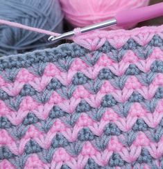 a crocheted blanket with yarn and knitting needles