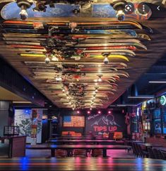 a room filled with lots of surfboards hanging from the ceiling and lights above it