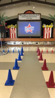 an empty bowling alley with blue and red cones in front of a large screen on the wall