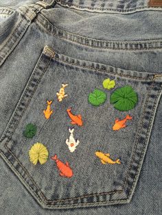 the back pocket of a pair of jeans with fish and lily pads on it