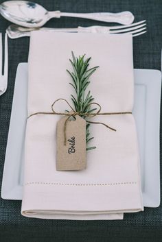 a place setting with napkins, silverware and an empty tag tied to it