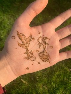 a person's hand with a tattoo on it that has flowers and leaves drawn on it