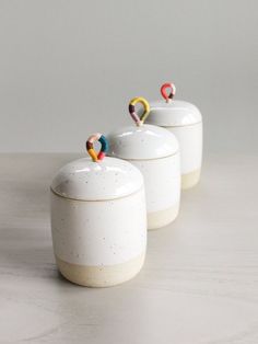 three ceramic containers with pins in them sitting on a table