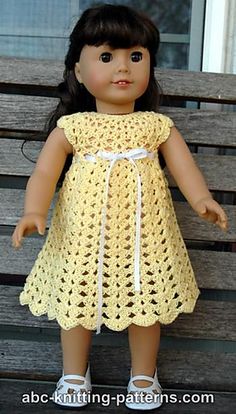 a doll is sitting on a bench wearing a yellow crochet dress and white shoes