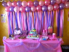 a table with pink, purple and blue balloons on it at a princess birthday party