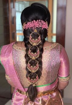 a woman with long hair wearing a pink and gold sari, braided into a bun