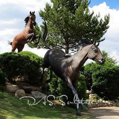 two statues of horses standing in the grass