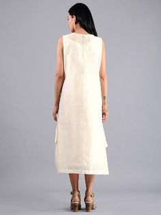 An ivory sleeveless side drape dress with handmade mirror and tassels in handwoven chanderi. This dress comes with a matching mul slip. Features: Handwoven chanderi cotton silk fabric Side drape and box pleat in front Highlight accents with mirror work Separate matching mul slip Handmade in India Measurements: Size XS : Bust-34", Waist-33", Hip-Flared, Shoulder-14", Length-47", Sleeve length-18" Size S : Bust-36", Waist-35", Hip-Flared, Shoulder-14.5", Length-47", Sleeve length-18" Size M : Bust Sleeveless Anarkali Cotton Kurta, Sleeveless Chanderi Dress With Chikankari Embroidery, Summer Chanderi Dress With Cutdana Detail, Sleeveless Chikankari Chanderi Dress, Summer Cutdana Chanderi Dress, Traditional Drape Chanderi Dress In Off White, Off White Chanderi Dress With Traditional Drape, Off White Chanderi Straight Kurta Dress, White Sleeveless Cotton Kurta