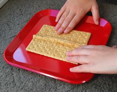 two hands reaching for crackers on a red plate