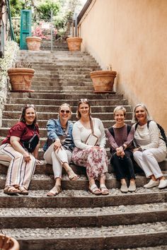 four women are sitting on the steps outside