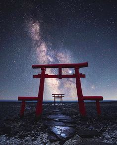 a large red structure sitting on top of a field under a sky filled with stars