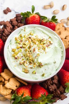 a bowl filled with whipped cream surrounded by nuts and strawberries on a white plate