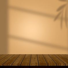 an empty wooden table in front of a wall with a bamboo plant shadow on it