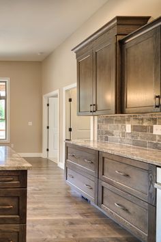 a large kitchen with wooden cabinets and marble counter tops, along with hardwood flooring