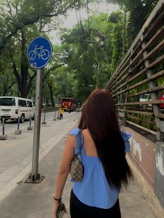 a woman is walking down the street with her back to the camera and she has long dark hair