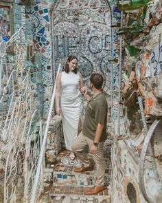 a man and woman are walking up some stairs with mosaic tiles on the walls behind them