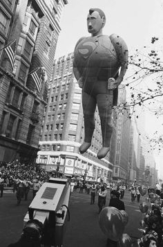 an inflatable balloon is being carried down the street by several people onlookers