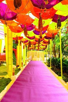 the walkway is lined with colorful umbrellas for an outdoor wedding ceremony or reception area