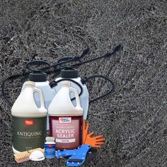 two gallon jugs of acrylic sealer sitting on the ground next to some tools