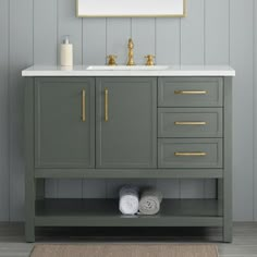 a bathroom vanity with a mirror above it and two towels on the floor next to it