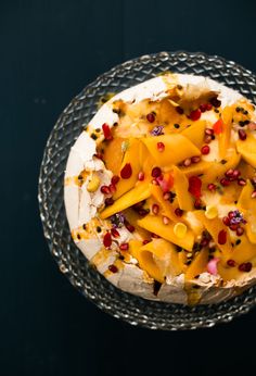 a cake covered in cheese and pomegranates on top of a glass plate