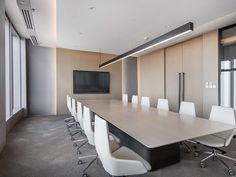 an empty conference room with white chairs and a flat screen tv mounted on the wall