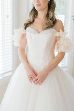 a woman in a white wedding dress with flowers on her shoulder