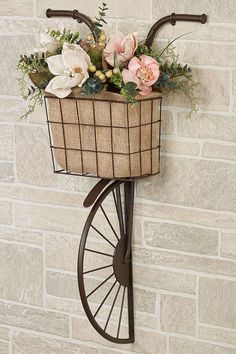 a bicycle basket mounted on the side of a brick wall with flowers growing out of it