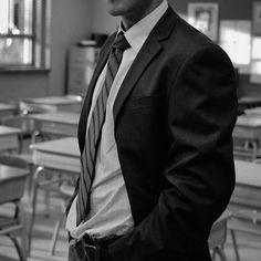 a man wearing a suit and tie standing in a classroom