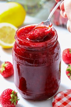 someone is holding a spoon full of strawberry jam